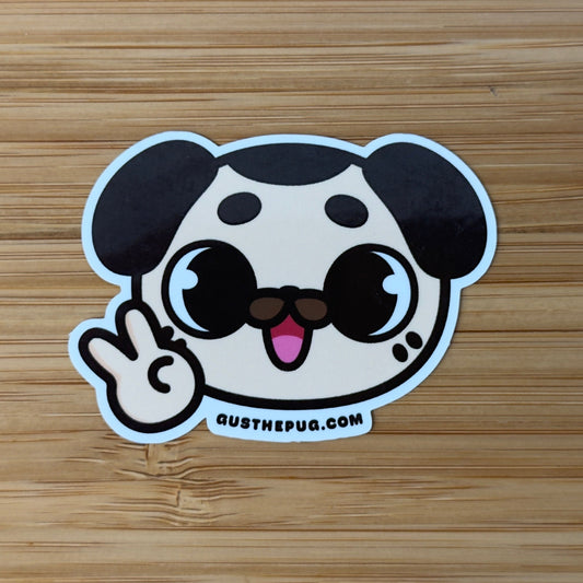 Cartoon dog sticker making a peace sign on a wooden surface
