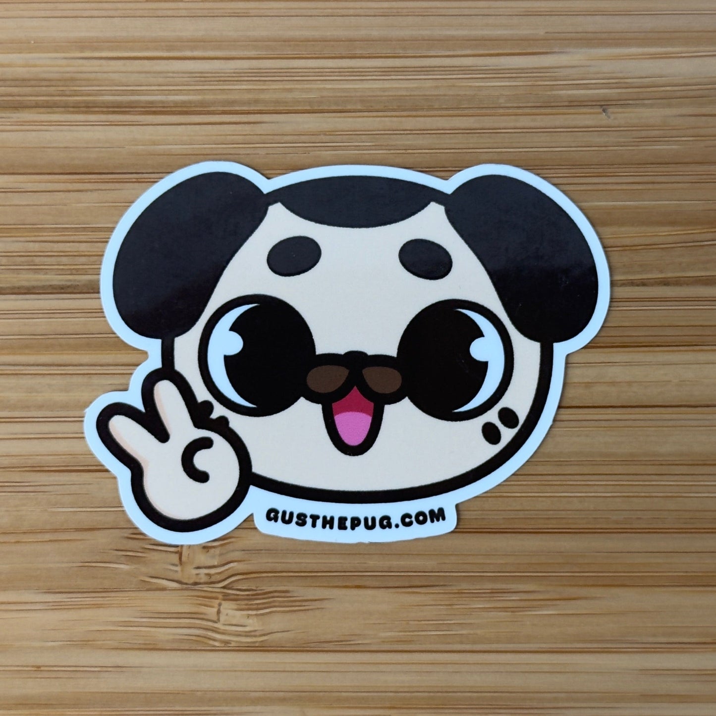 Cartoon dog sticker making a peace sign on a wooden surface
