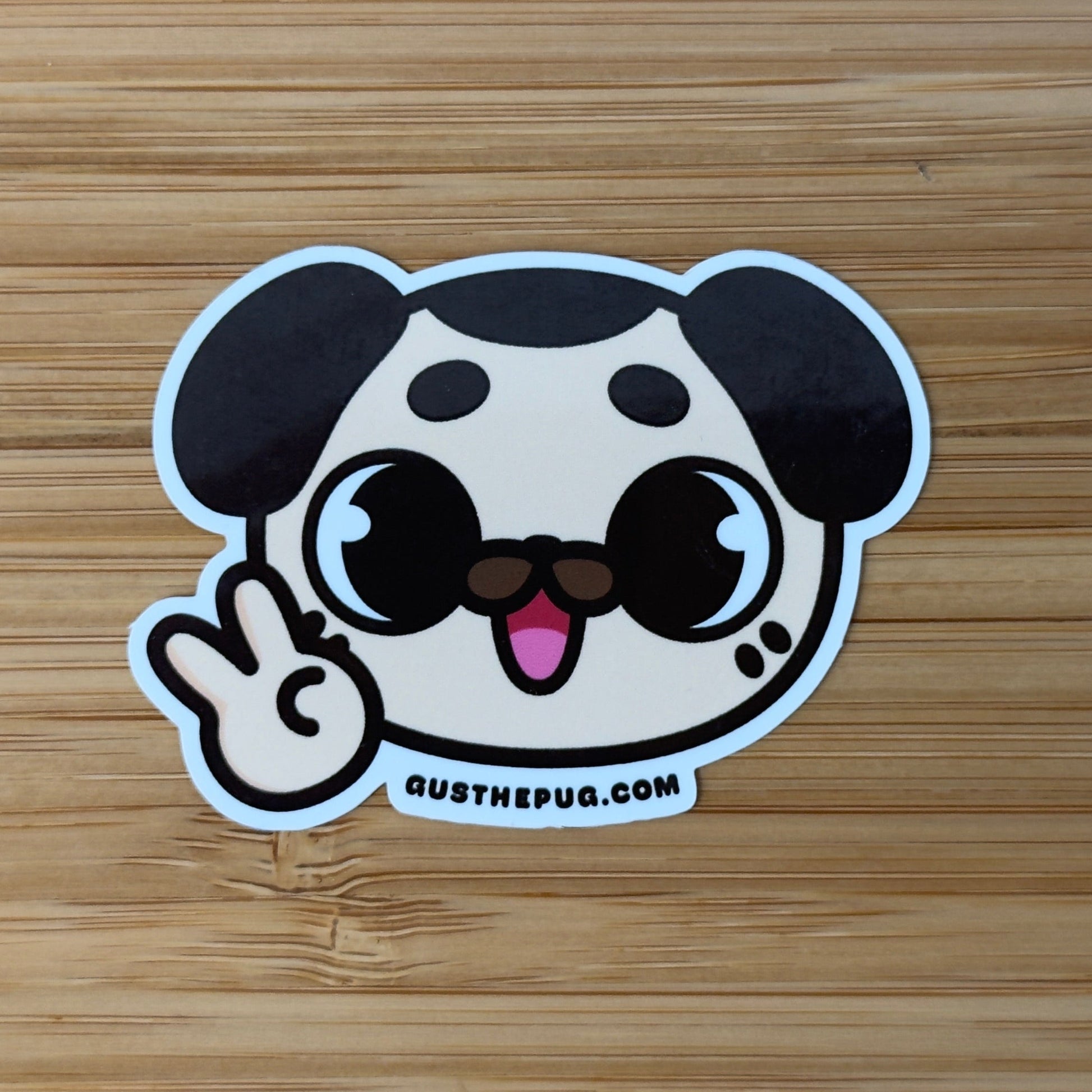 Cartoon dog sticker making a peace sign on a wooden surface